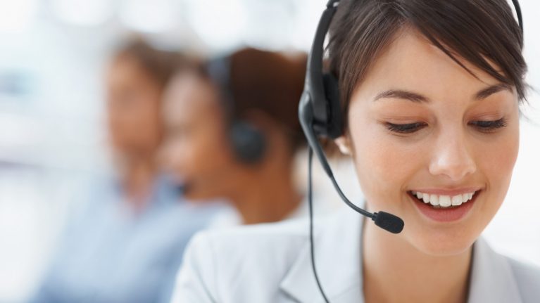 Beautiful customer representative with headset smiling during a telephone conversation